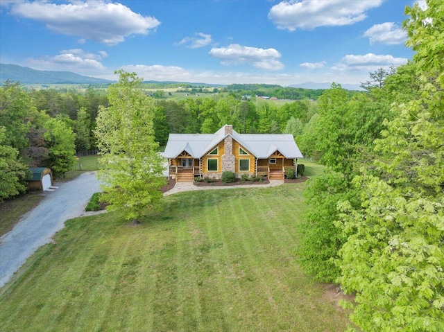 view of subject property with a mountain backdrop and a heavily wooded area