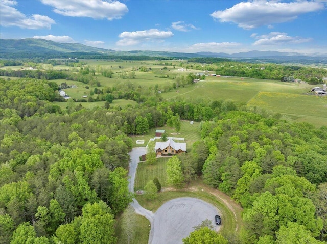 aerial view of property's location with a mountain backdrop, a heavily wooded area, and rural landscape