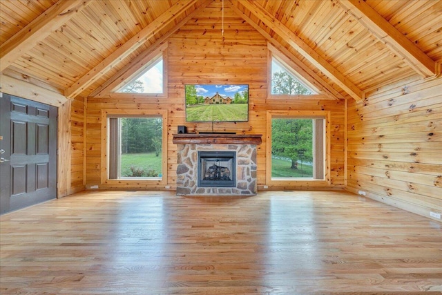 unfurnished living room featuring wood walls, wooden ceiling, beamed ceiling, a fireplace, and light wood finished floors