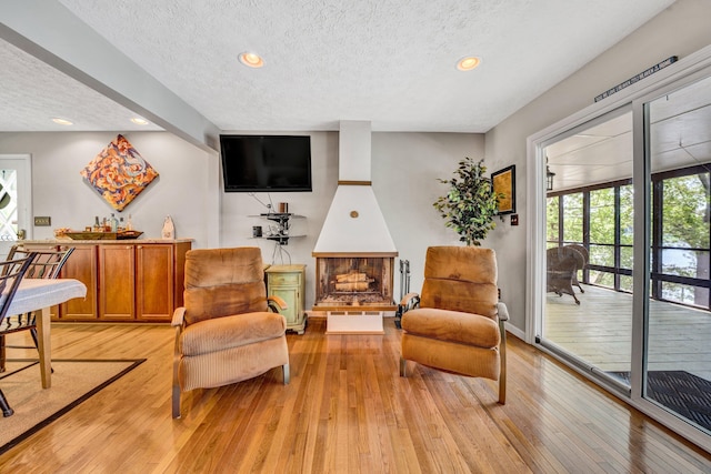 living area with a textured ceiling, light wood-style floors, and recessed lighting