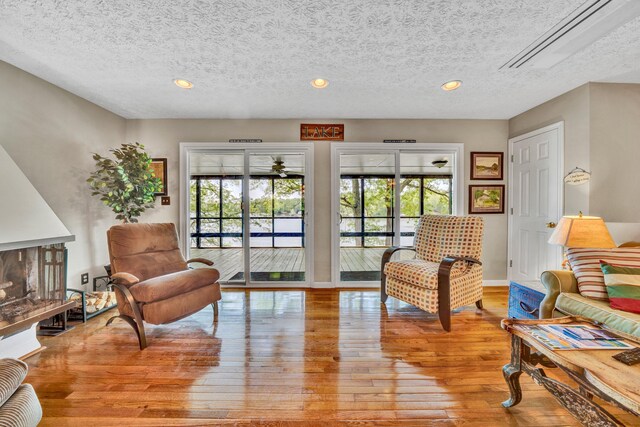 sitting room featuring attic access, wood-type flooring, a textured ceiling, recessed lighting, and baseboards