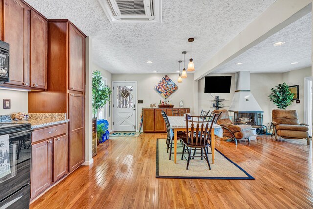 dining space featuring light wood-style floors, a textured ceiling, and recessed lighting