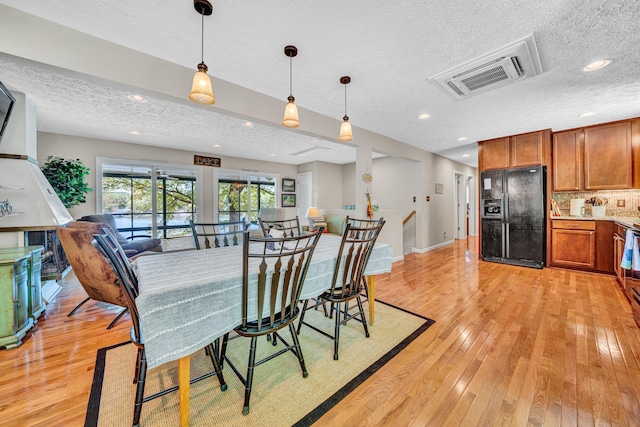 dining room featuring a textured ceiling, light wood-style floors, recessed lighting, and baseboards