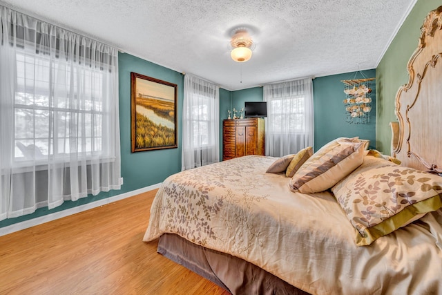bedroom featuring a textured ceiling, wood finished floors, and baseboards