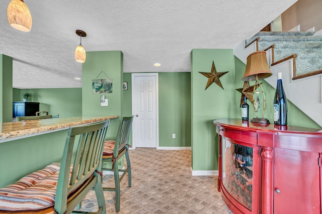 interior space featuring a dry bar, a textured ceiling, baseboards, carpet, and recessed lighting
