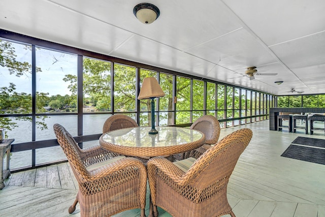 sunroom / solarium with a ceiling fan, a water view, and outdoor dining area