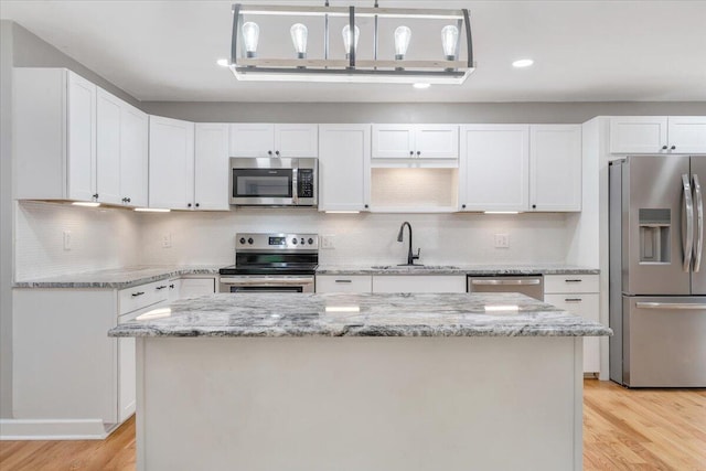 kitchen with stainless steel appliances, a sink, white cabinets, light wood finished floors, and recessed lighting