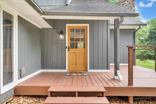 doorway to property with roof with shingles, a chimney, and a wooden deck