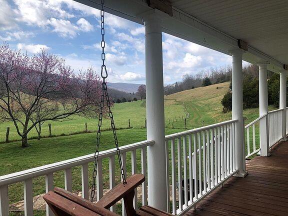 wooden terrace with covered porch, a yard, and a view of rural / pastoral area