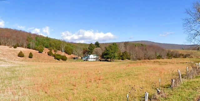 view of mountain background featuring rural landscape and a heavily wooded area