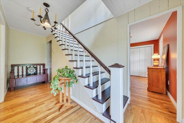 stairs with wood finished floors and a chandelier