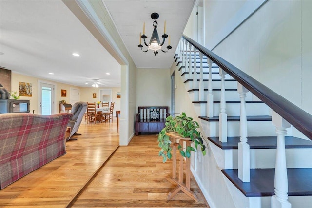 stairway featuring wood finished floors, recessed lighting, a ceiling fan, and a chandelier