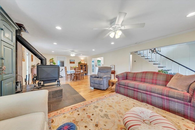 living room featuring a wood stove, a ceiling fan, stairway, light wood-style flooring, and recessed lighting