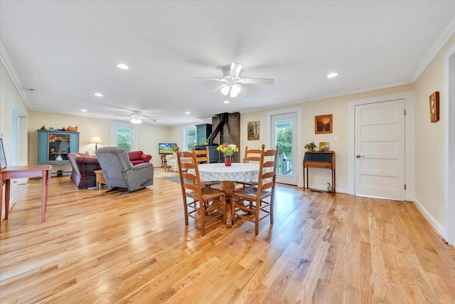 dining space featuring a wood stove, ornamental molding, light wood finished floors, a ceiling fan, and recessed lighting