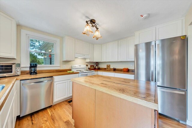 kitchen featuring stainless steel appliances, wood counters, under cabinet range hood, white cabinets, and light wood finished floors