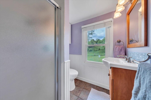 bathroom featuring wainscoting, a stall shower, vanity, toilet, and tile patterned floors