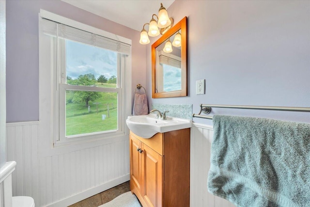 bathroom with wainscoting, vanity, and toilet