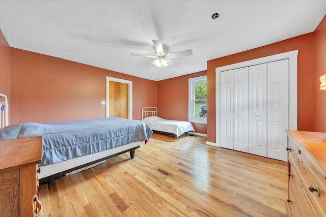bedroom with light wood-style floors, a closet, ceiling fan, and baseboards
