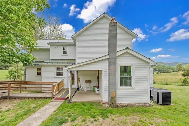 rear view of house featuring cooling unit, a patio, and metal roof