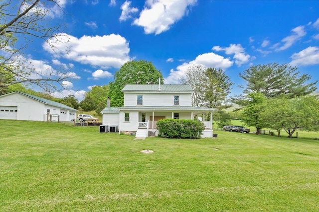 rear view of property featuring a porch, a garage, a yard, and metal roof