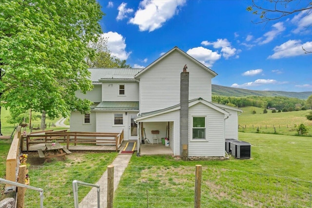 rear view of house with central AC, a yard, and metal roof