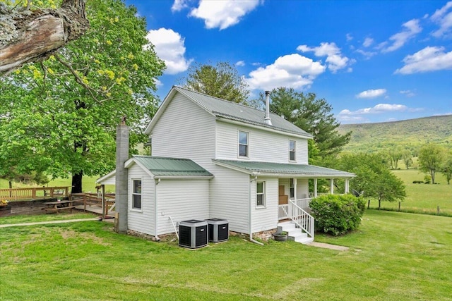 rear view of house with metal roof, central AC, covered porch, and a yard
