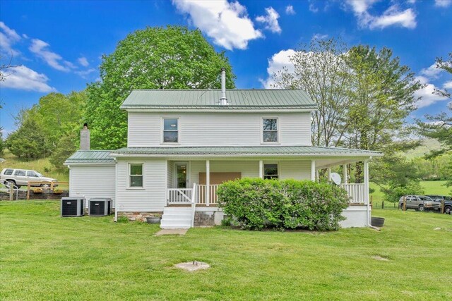 back of house featuring covered porch, a lawn, metal roof, and central AC