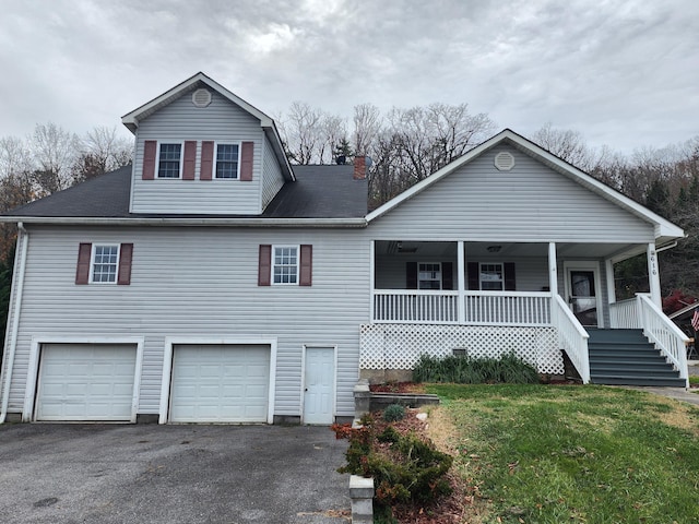 view of front of house with a garage, driveway, a front yard, covered porch, and stairs