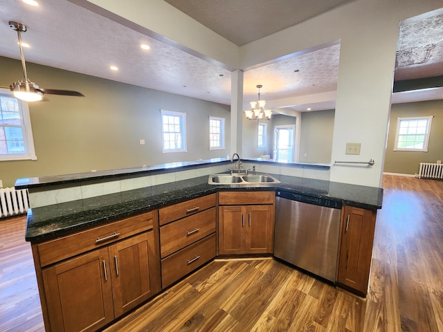 kitchen featuring dishwasher, a sink, brown cabinets, open floor plan, and dark wood-style flooring