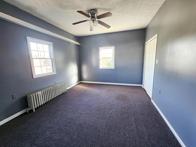 spare room with radiator, a ceiling fan, healthy amount of natural light, a textured ceiling, and carpet floors