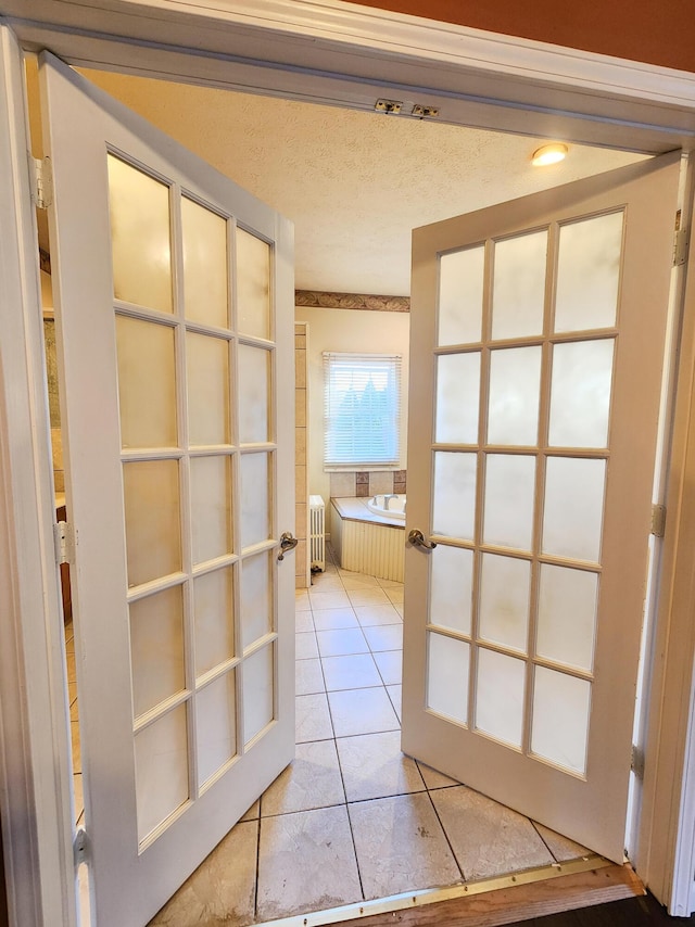 full bathroom featuring french doors, a bath, tile patterned floors, radiator, and a textured ceiling