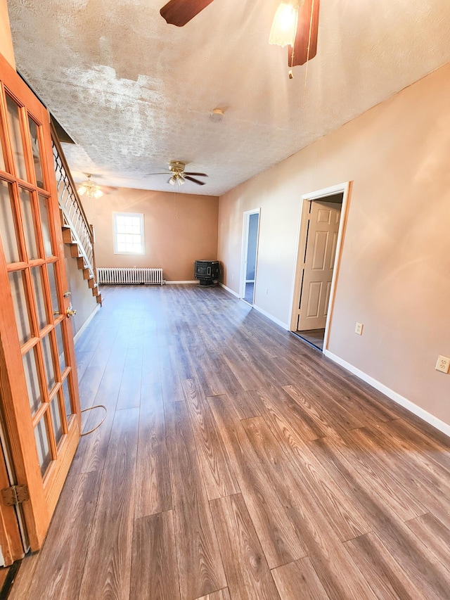 unfurnished living room featuring wood finished floors, a ceiling fan, baseboards, and radiator heating unit