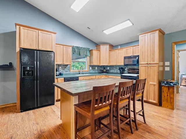 kitchen with black appliances, light brown cabinetry, lofted ceiling, wood counters, and light wood-style flooring