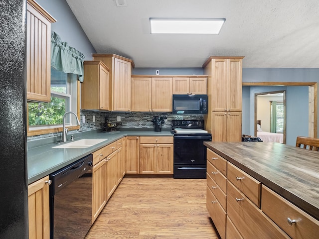 kitchen featuring black appliances, a sink, light wood-style floors, light brown cabinets, and decorative backsplash