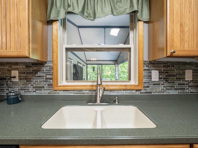 kitchen view of a sink, dark countertops, and decorative backsplash