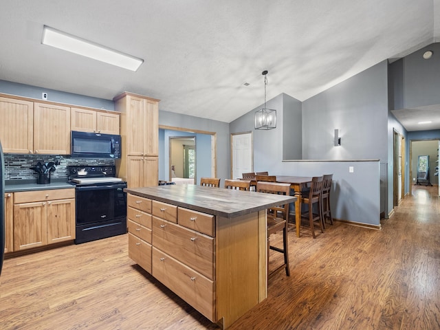 kitchen featuring black appliances, light brown cabinetry, vaulted ceiling, a breakfast bar, and light wood finished floors