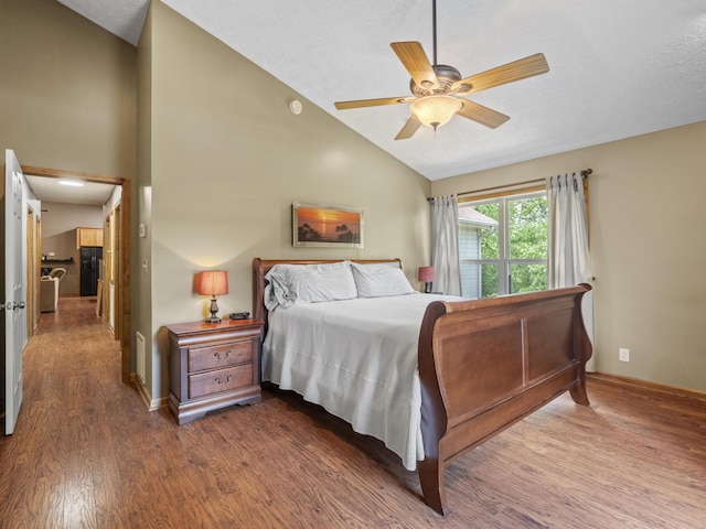 bedroom featuring lofted ceiling, dark wood-style floors, a ceiling fan, and baseboards
