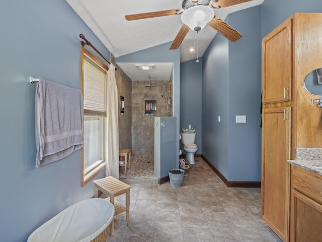 bathroom with a ceiling fan, a tile shower, toilet, lofted ceiling, and baseboards