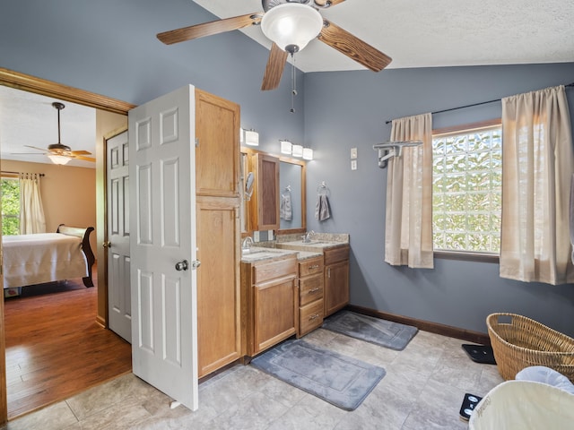 full bathroom featuring ceiling fan, vaulted ceiling, ensuite bath, vanity, and baseboards