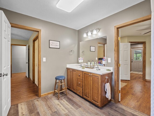 bathroom with wood finished floors, double vanity, and baseboards