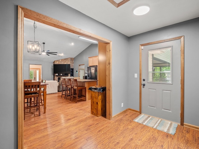 entrance foyer with light wood-type flooring, a chandelier, lofted ceiling, and baseboards