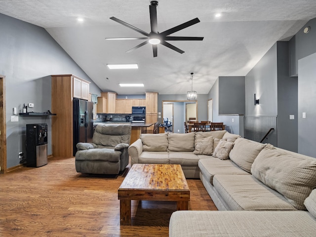 living area with vaulted ceiling, ceiling fan, and light wood-style flooring