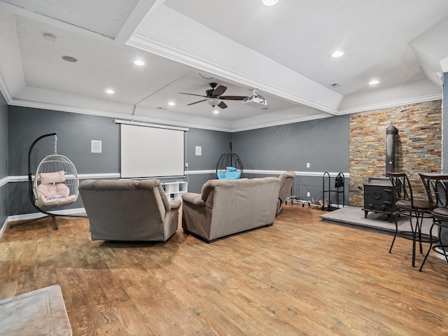 living area featuring a wood stove, wood finished floors, a ceiling fan, ornamental molding, and recessed lighting