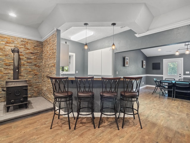 community bar area with light wood-style flooring, a wood stove, and hanging light fixtures