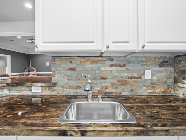 kitchen with a sink, tasteful backsplash, white cabinets, and recessed lighting
