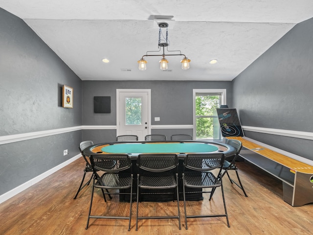 game room featuring wood finished floors, lofted ceiling, a textured wall, and baseboards