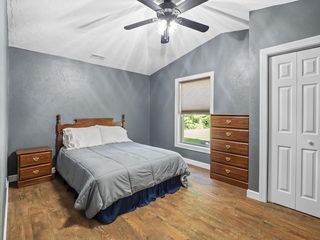 bedroom featuring lofted ceiling, wood finished floors, a closet, a ceiling fan, and a textured wall