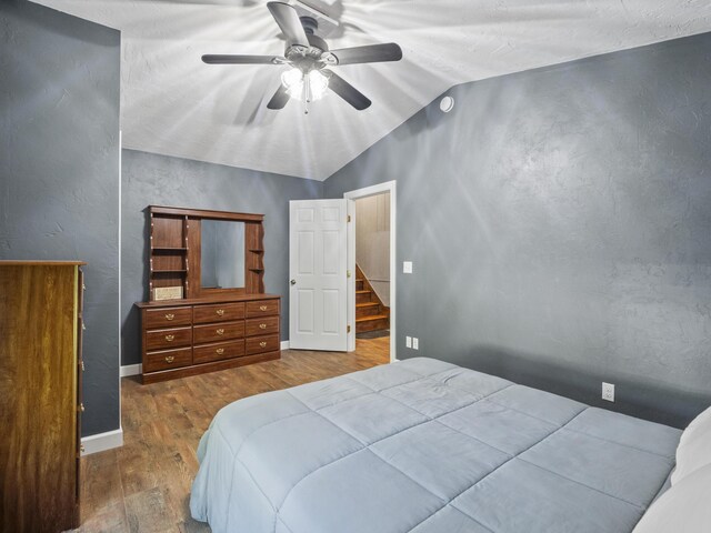 bedroom with wood finished floors, vaulted ceiling, ceiling fan, and baseboards