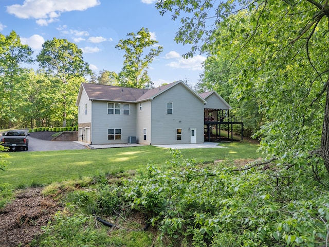 back of house featuring cooling unit, a patio area, a yard, and a garage
