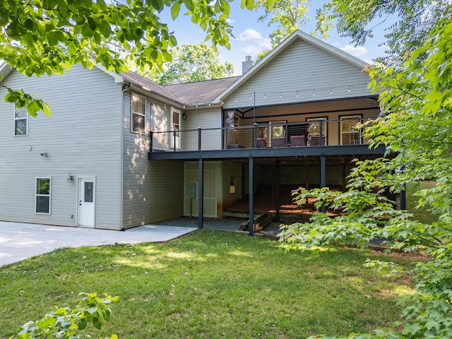 back of property with a lawn, a chimney, a wooden deck, and a patio area